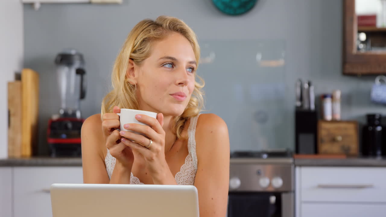 una rubia linda usando una computadora portátil en la cocina