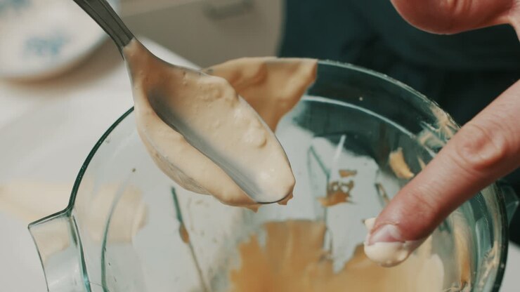 Close up on spoon, chef checks consistency of homemade delicious mayonnaise