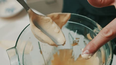 close up on spoon, chef checks consistency of homemade delicious mayonnaise