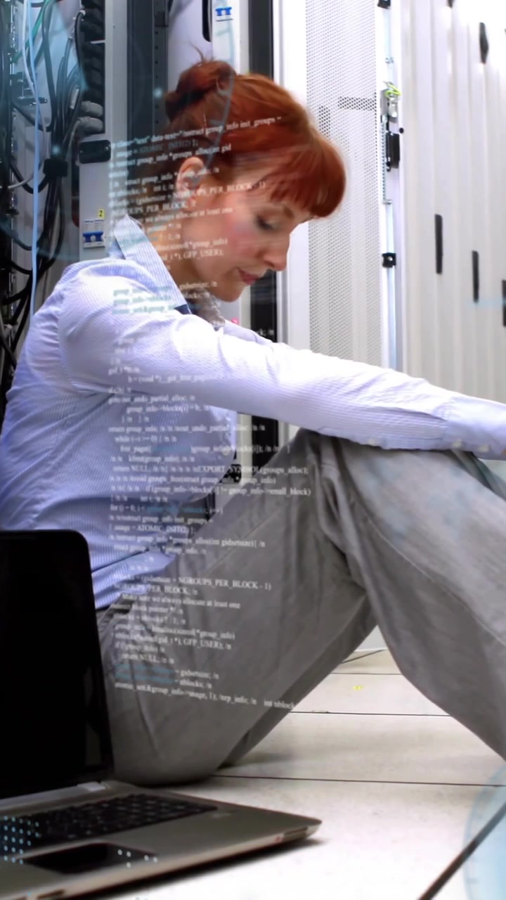 Frau sitzt im Serverraum auf dem Boden, benutzt Laptop und schaut Animation.