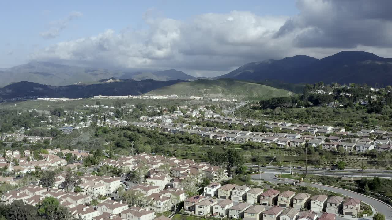 Los Angeles mountainside residential suburb, dark clouds over hills, aerial