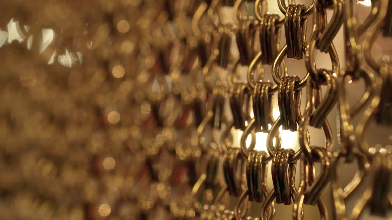 긴 금 사슬의 느리고 부드러운 움직임, 균일한 스, 휴식을 위한 금색 배경, 명상, 휴식, 진정시키기 위한 질감, 반이는 빛, 아래에서 위로 보이는 광경, 흐릿한 빛.