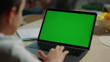 Niño-Desconocido-Usando-Una-Computadora-De-Maqueta-En-Casa.-Colegial-Mirando-La-Pantalla-Verde-Del-Portátil