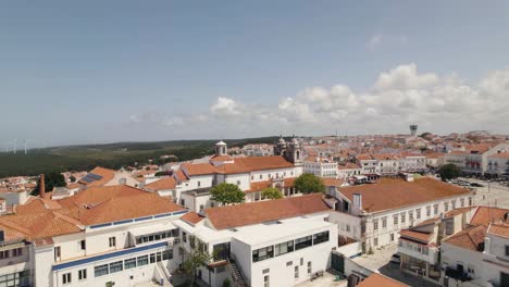 Toma-Panorámica-Cinematográfica-Con-Vistas-Al-Hermoso-Paisaje-Urbano-De-Nazare-Y-La-Famosa-Iglesia-En-La-Plaza-Central