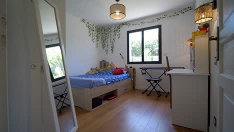 entrance into a teenager's bedroom, a white desk, a double bed with drawer, a piano and climbing plants as decoration