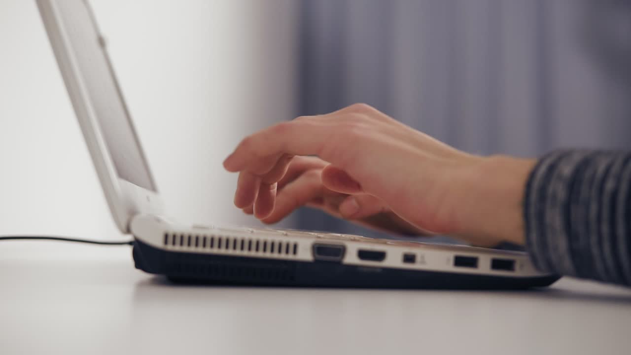 Close Up of business woman's hands typing on laptop keyboard. Side view of female hands typing on a laptop. Slow Motion shot