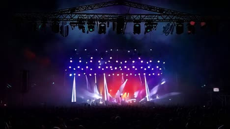 rock band performing on stage captivates a large audience with colorful lights and energetic music during a live concert