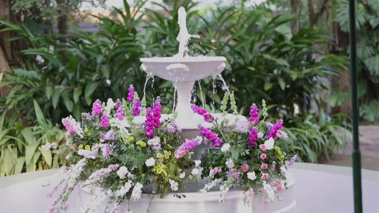 Movimento al rallentatore di una fontana floreale, ambientazione serena in un giardino, atmosfera rilassante