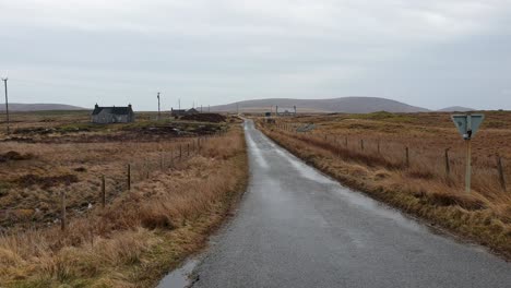 a rural road stretches through a desolate landscape under an overcast sky