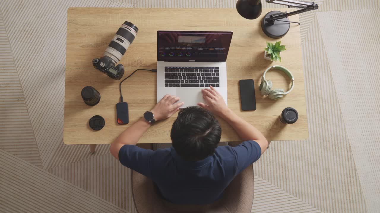 Top View Of A Male Color Grading Celebrating Succeed Using A Laptop Next To The Camera Editing The Video In The Workspace At Home