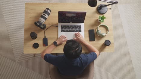 top view of a male color grading celebrating succeed using a laptop next to the camera editing the video in the workspace at home