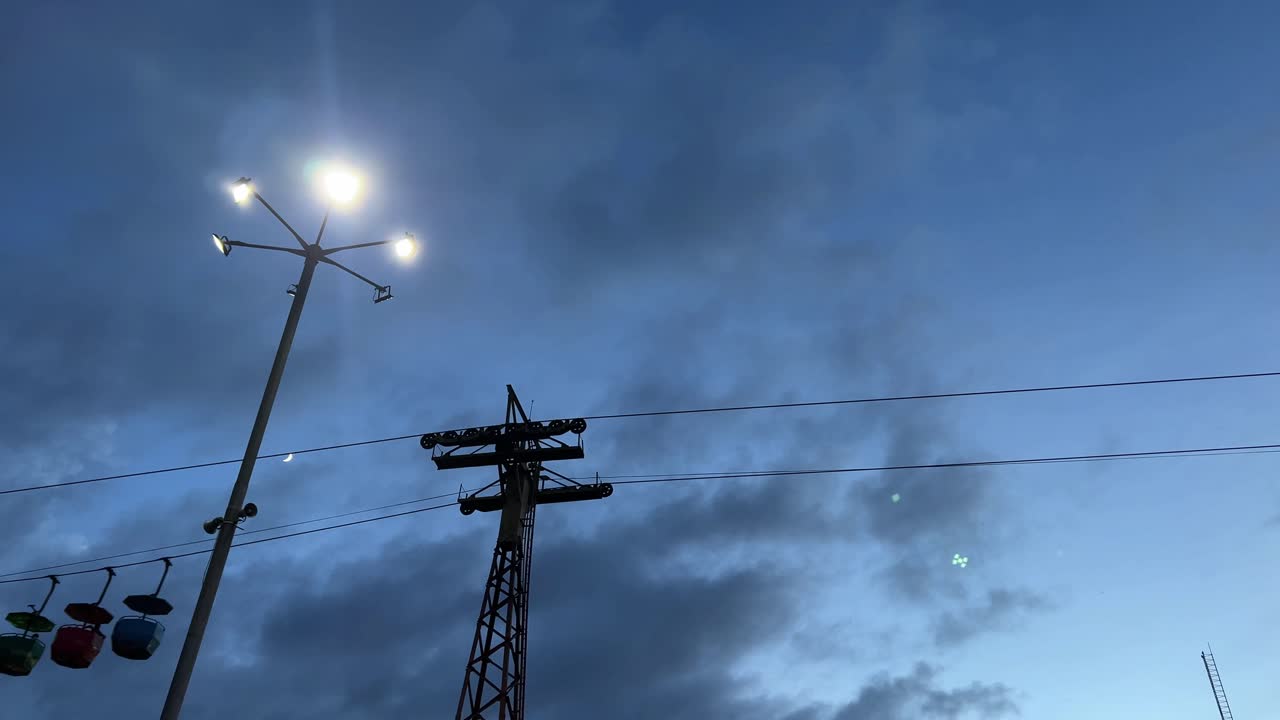 Silhouette of three moving cable car in a blue sky background.