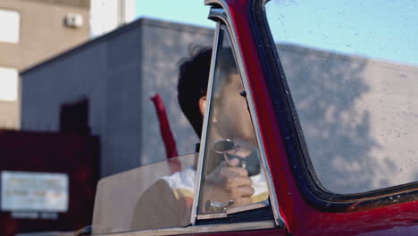 man looking out of a vintage red car window