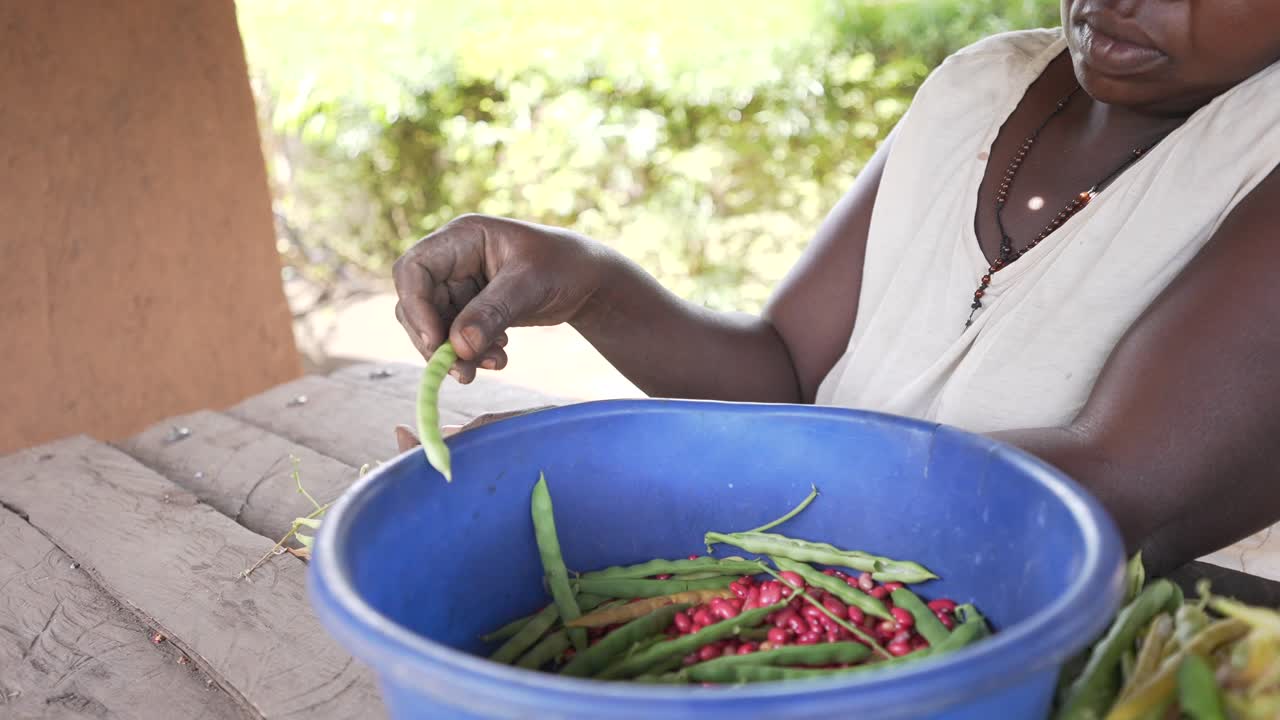 Local African black woman peeling and cooking red kidney beans