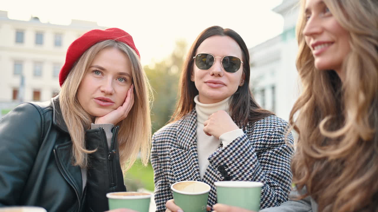 Three women talking and drinking coffee at a terrace