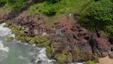 disparo de un dron orbital de 4k de una hermosa joven india de 27 años con un vestido floral blanco y azul sola disfrutando de la serenidad en la cima de un acantilado rodeado de vegetación cerca de la orilla del mar