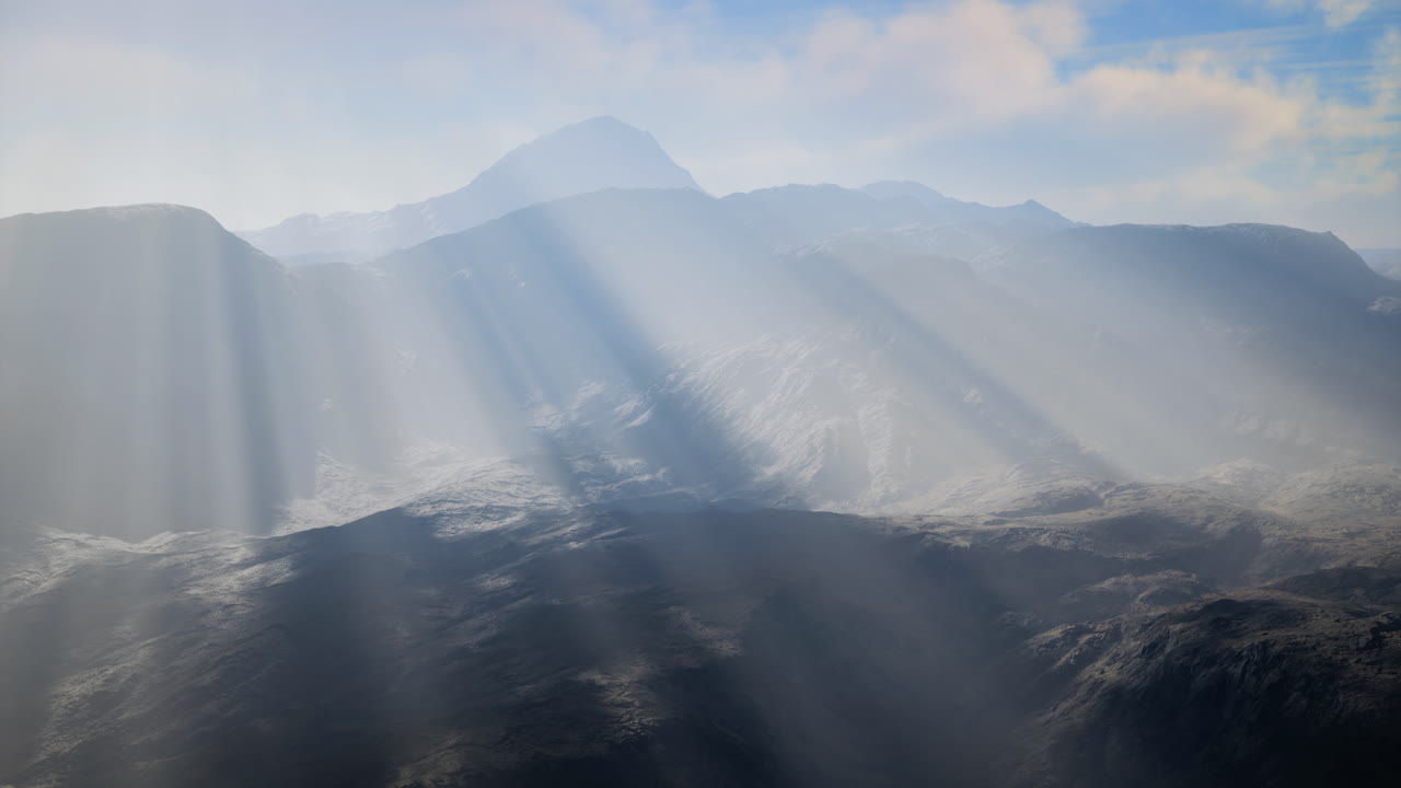 Sunlight pierces clouds over mountains creating a serene scene