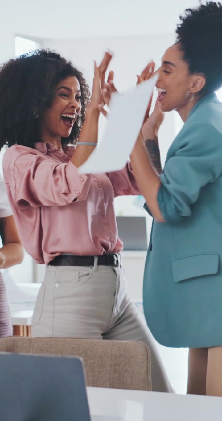 Excited Businesswomen Celebrating Success by Throwing Papers in Office