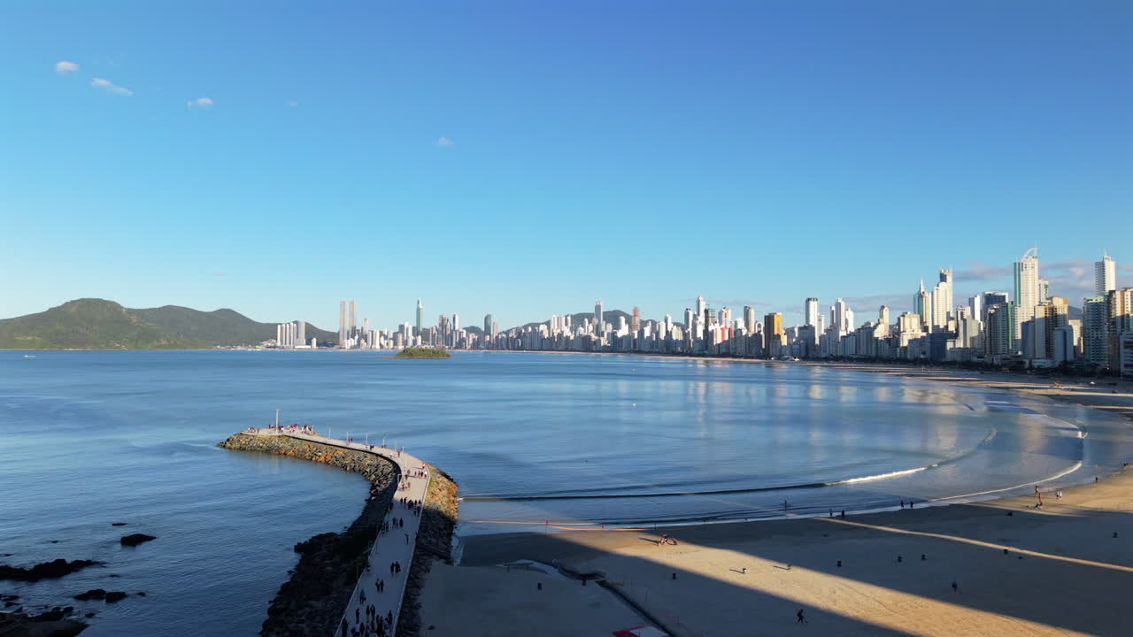 Panoramic drone fly to the Balneário Camboriú curving Atlantic Ocean beachside with city skyline, Santa Catarina, Brazil