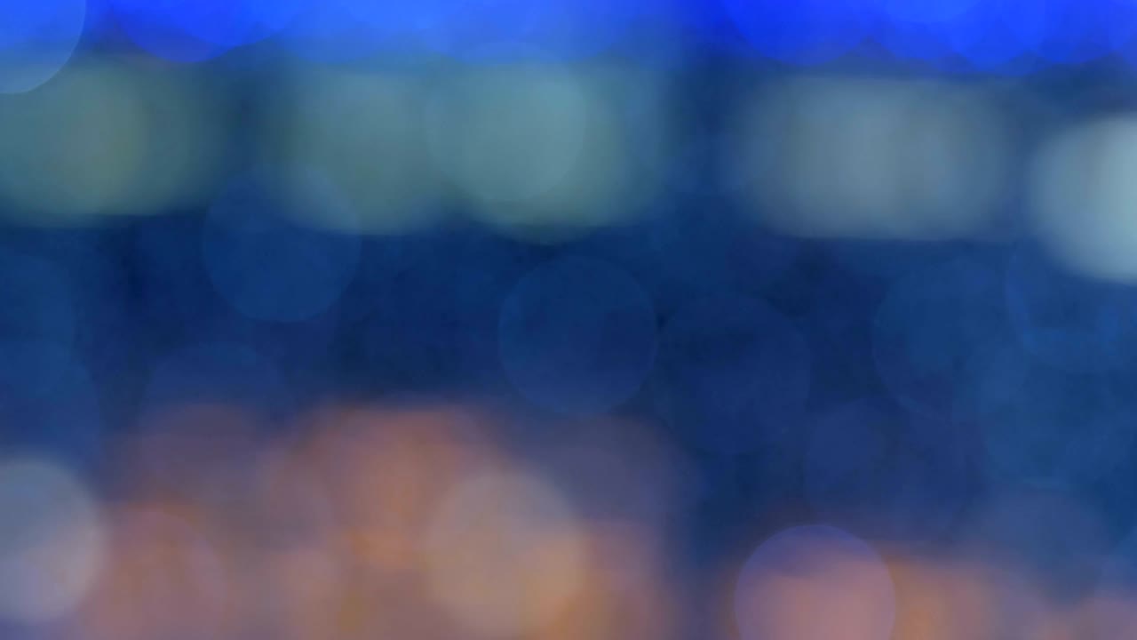 밤의 추상적인 배경은 멋진 보케로 분해되어 있습니다. 흐릿한 크리스마스 조명 보케. 흐릿함을 가로질러 팬.