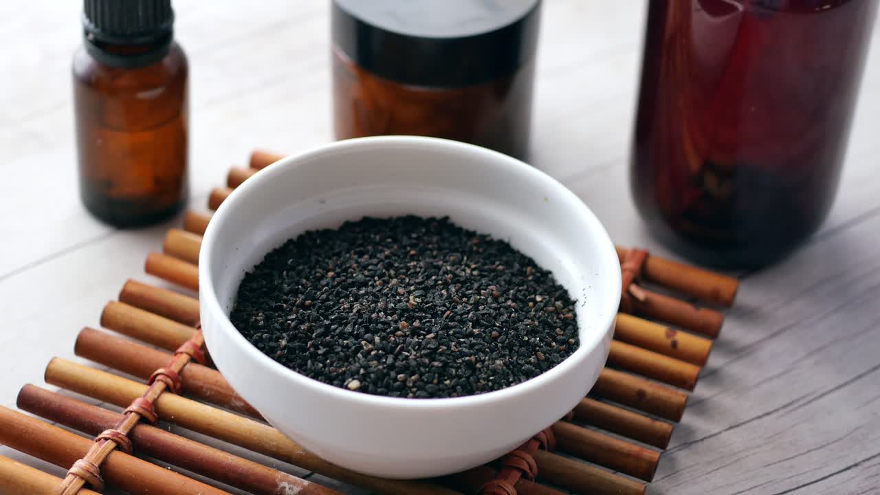 Cumino nero al cucchiaio con olio in un barattolo sul tavolo