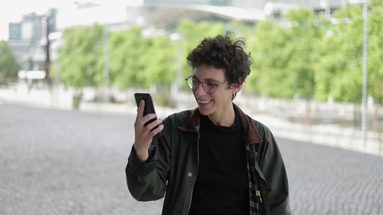 mujer sonriente hablando durante el chat de video al aire libre