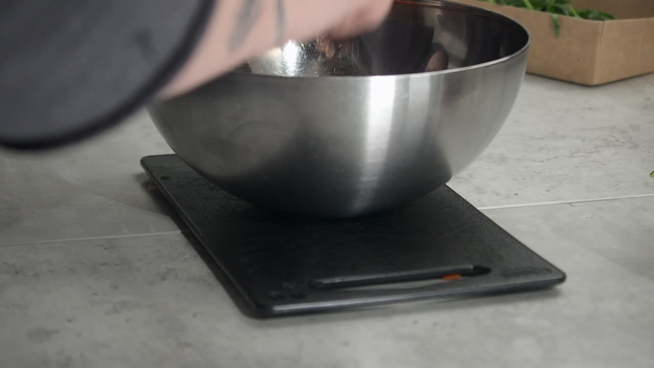 Close up: Chef adds chopped red bell pepper to metal mixing bowl