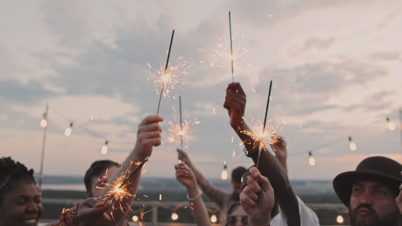 Glade mennesker holder stjernekastere til rooftop-fest