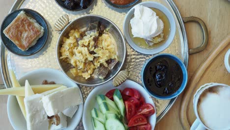 turkish breakfast with cheese, eggs, tomatoes, cucumbers, honey, jam, coffee, and pastry