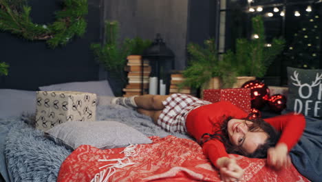 happy girl enjoys christmas at home. young woman on bed resting during new year. joyful mood of a pretty female at christmas.