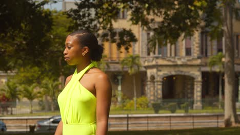 a natural hair black woman walks in a park with stollmeyer castle in the background on the caribbean island of trinidad