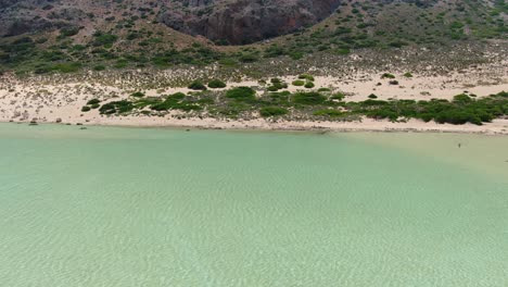 The-mountainside-in-Balos-Beach-on-the-island-of-Crete-Greece-where-the-saltwater-lagoon-meets-the-land,-Aerial-drone-flyover-shot