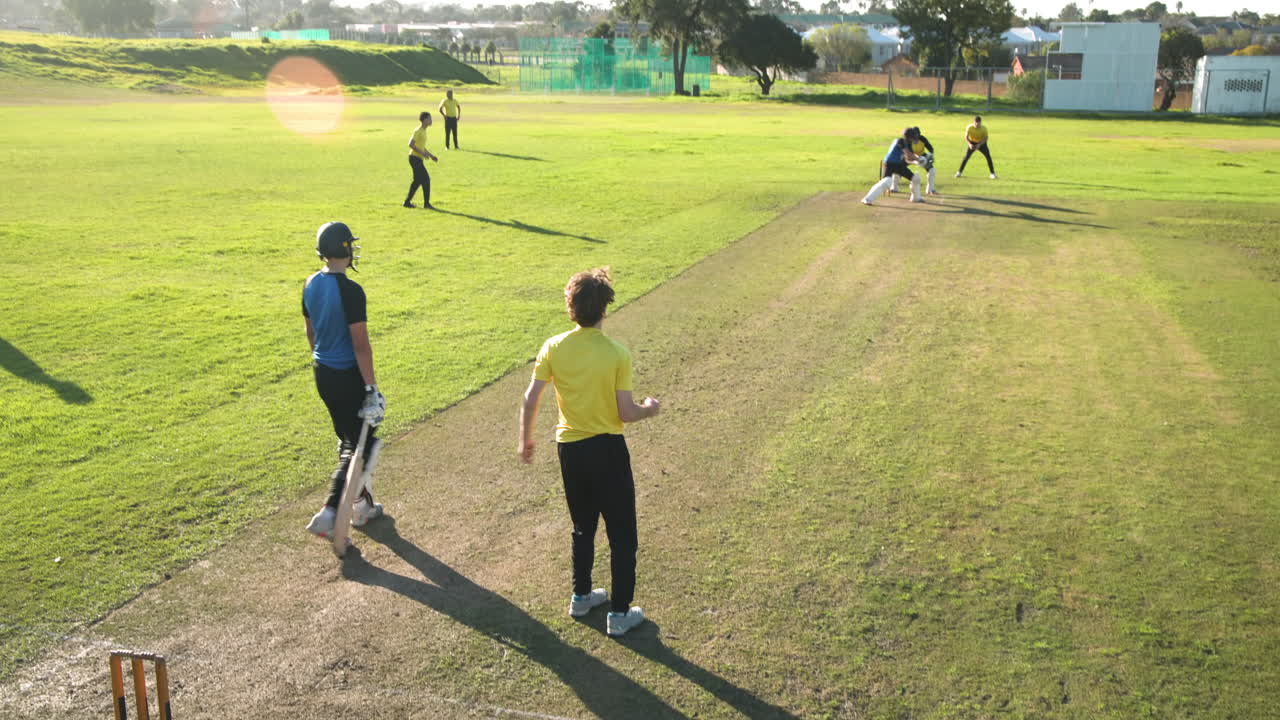 Cricket players practicing on sunny field, focusing on batting and teamwork