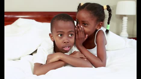 Cute-siblings-whispering-in-bed