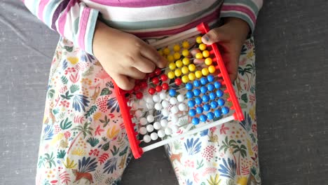 vista superior de un niño jugando con un juguete de ábaco