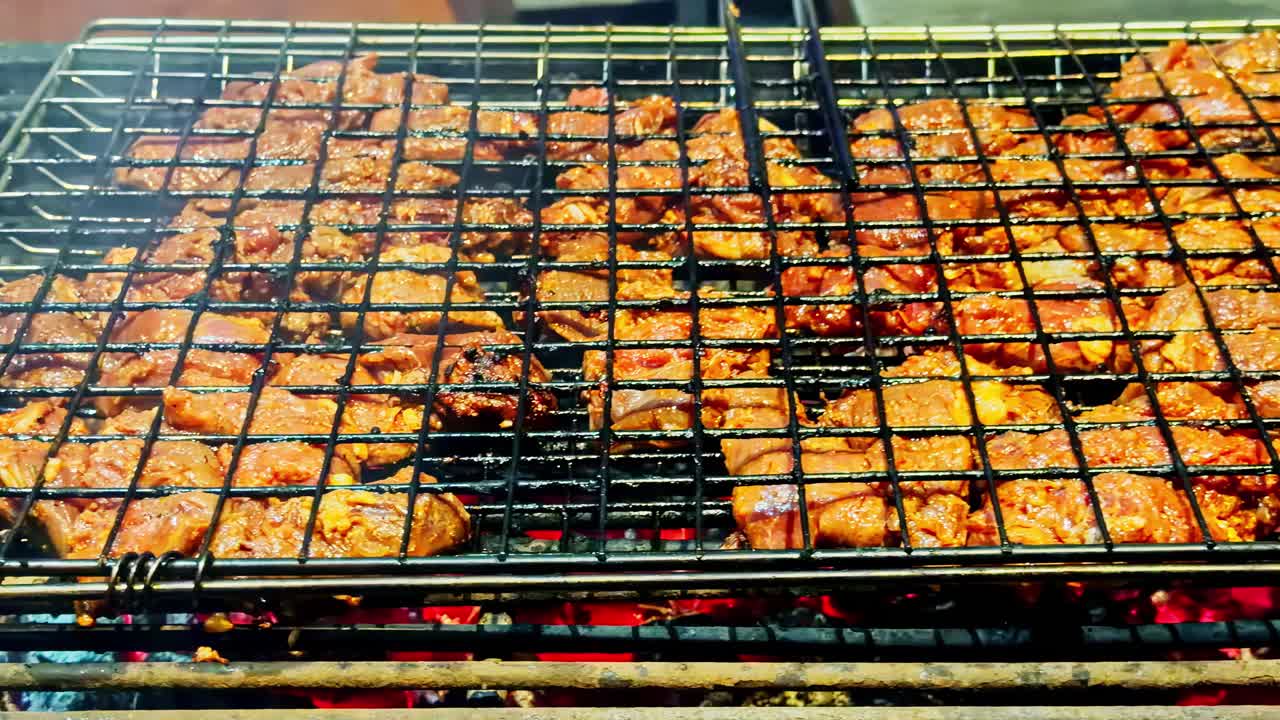 Grilled kebabs cooking on skewers in double sided grill at Sharm El Sheikh night market