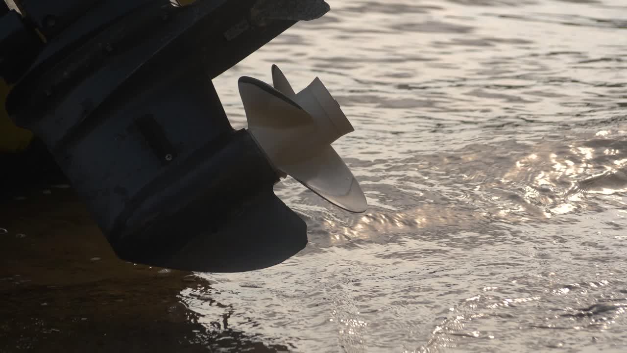 Lower unit propeller of an outboard motor on a boat near the water edge