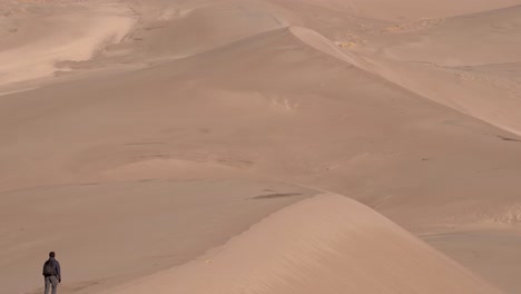 man walking over sand dunes on a sunny day