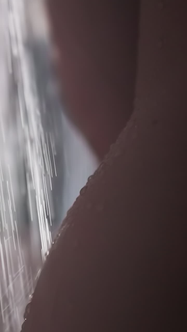 벌거벗은 여자가 샤워실에서 물 흐름 아래에서 는다. 벌거 벗은 여자가 신선한 샤워를 즐기고 서 있다. 벌거벗는 여자가 에서 물의 폭포 아래 서 있다.