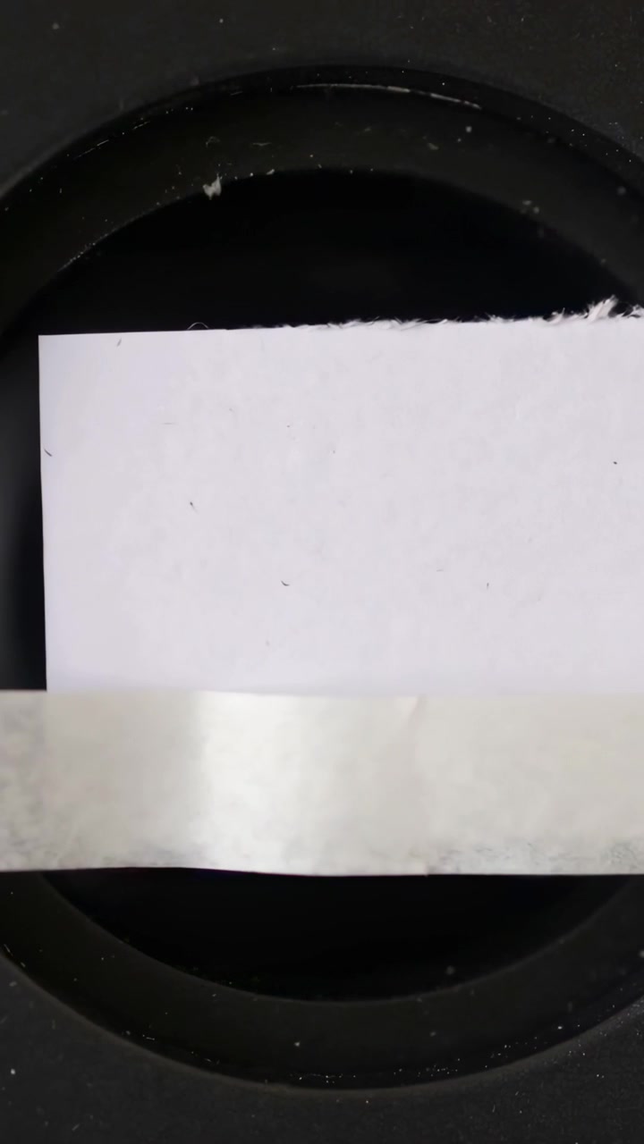 Vertical video: Sliding torn white paper offframe hand pulling tape exposing dark rim close-up