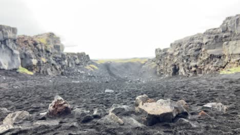 hombre sosteniendo un puñado de arena volcánica negra en islandia