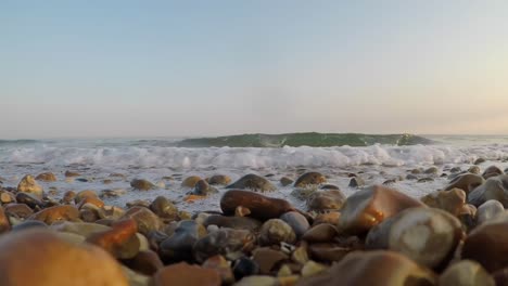 waves break on the shore and over the camera, low down shot