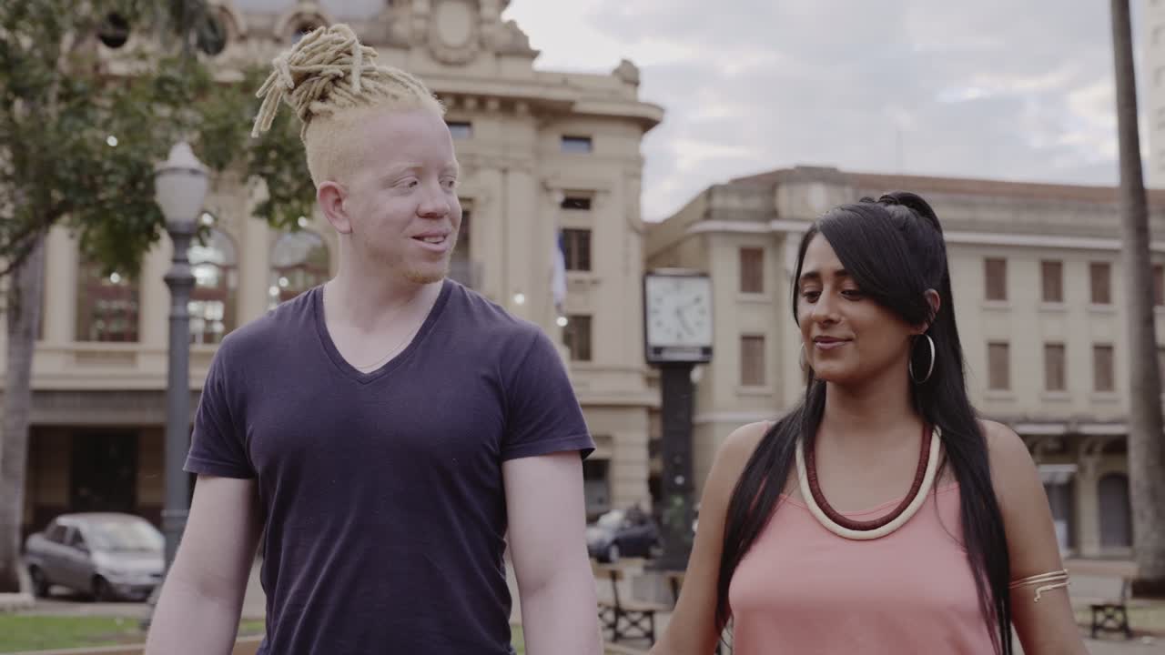 A diverse couple walking and talking in a city park