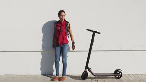 African-american-woman-standing-next-to-scooter-on-promenade-by-the-sea