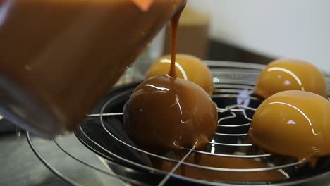 Process-of-creating-delicious-dessserts.-Covering-baked-cakes-with-glazing.-Second-layer-of-caramel-on-top.-Close-up-footage.