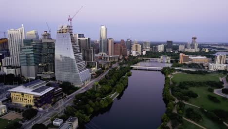 Flying-over-bridges-on-the-Colorado-river,-twilight-in-Austin,-USA---Aerial-view