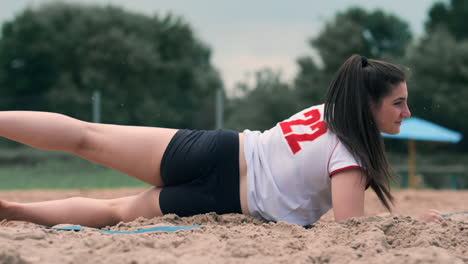 movimiento lento: una mujer joven saltando en la caída golpea la pelota en la arena. jugador de voleibol hace un equipo y juega la pelota fuera en la caída.
