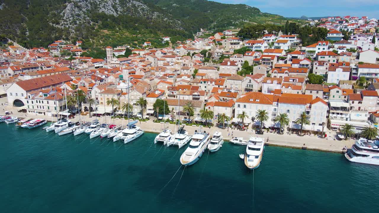 Panorama de uma cidade costeira com muitas casas de telhados vermelhos, rodeada pelo mar e montanhas
