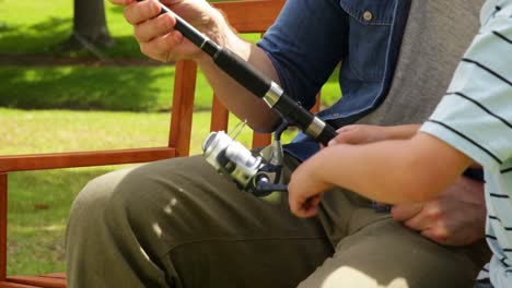 Father-teaching-his-young-son-how-to-fish-on-a-bench