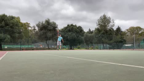 Hombre-Joven-Y-Atlético-Haciendo-Servicio-Y-Haciendo-Un-Gran-éxito-Para-Ganar-El-Punto-Con-Una-Camiseta-Azul-En-Un-Día-Nublado-En-Lisboa